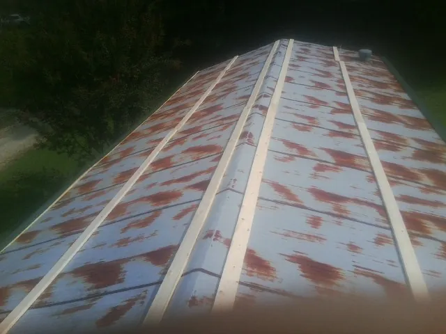 Rusted metal roof panels with new wood purlins before replacement — Storm Damage Roof Repair in Shambaugh by Roofing Brothers
