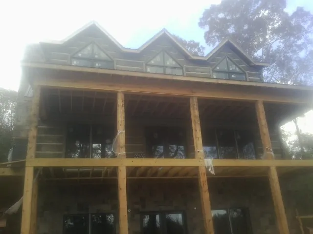 Dormers and porch framing on a large log home under construction — Roof Coating work by our crew in Shambaugh