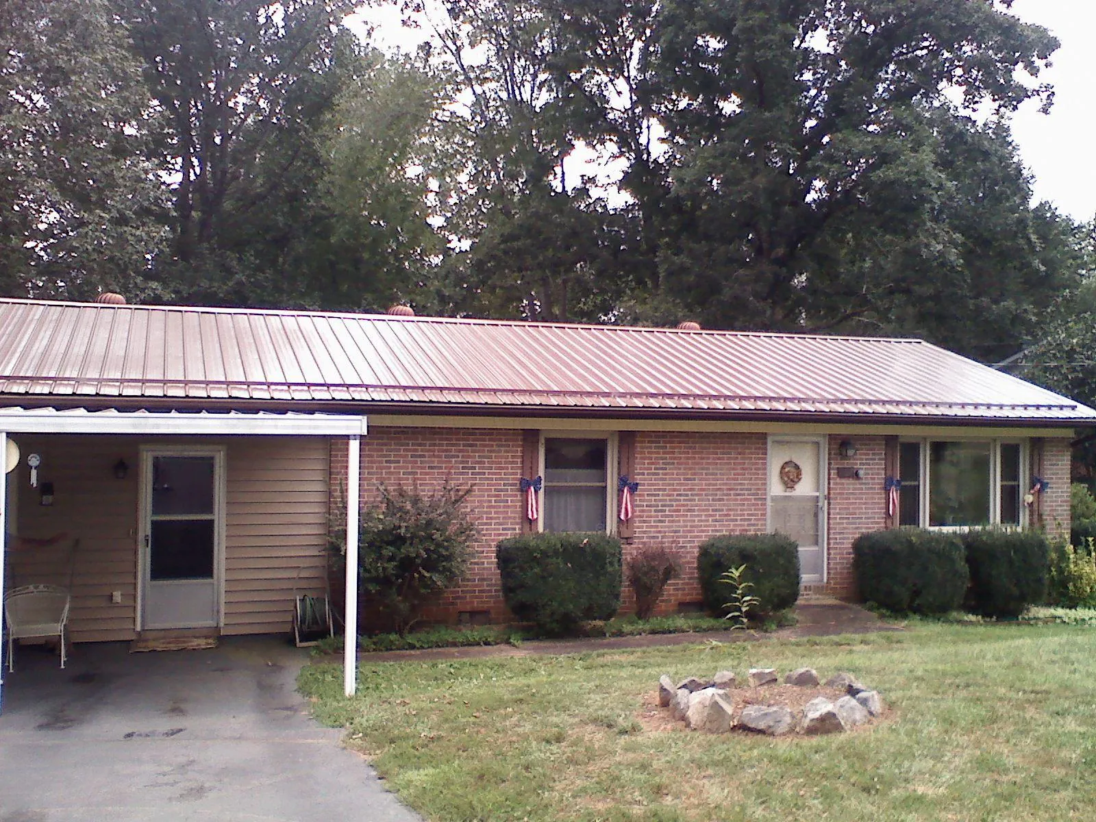 Bronze metal roof and carport on a brick ranch home — Roof Repair work by our crew in Shambaugh