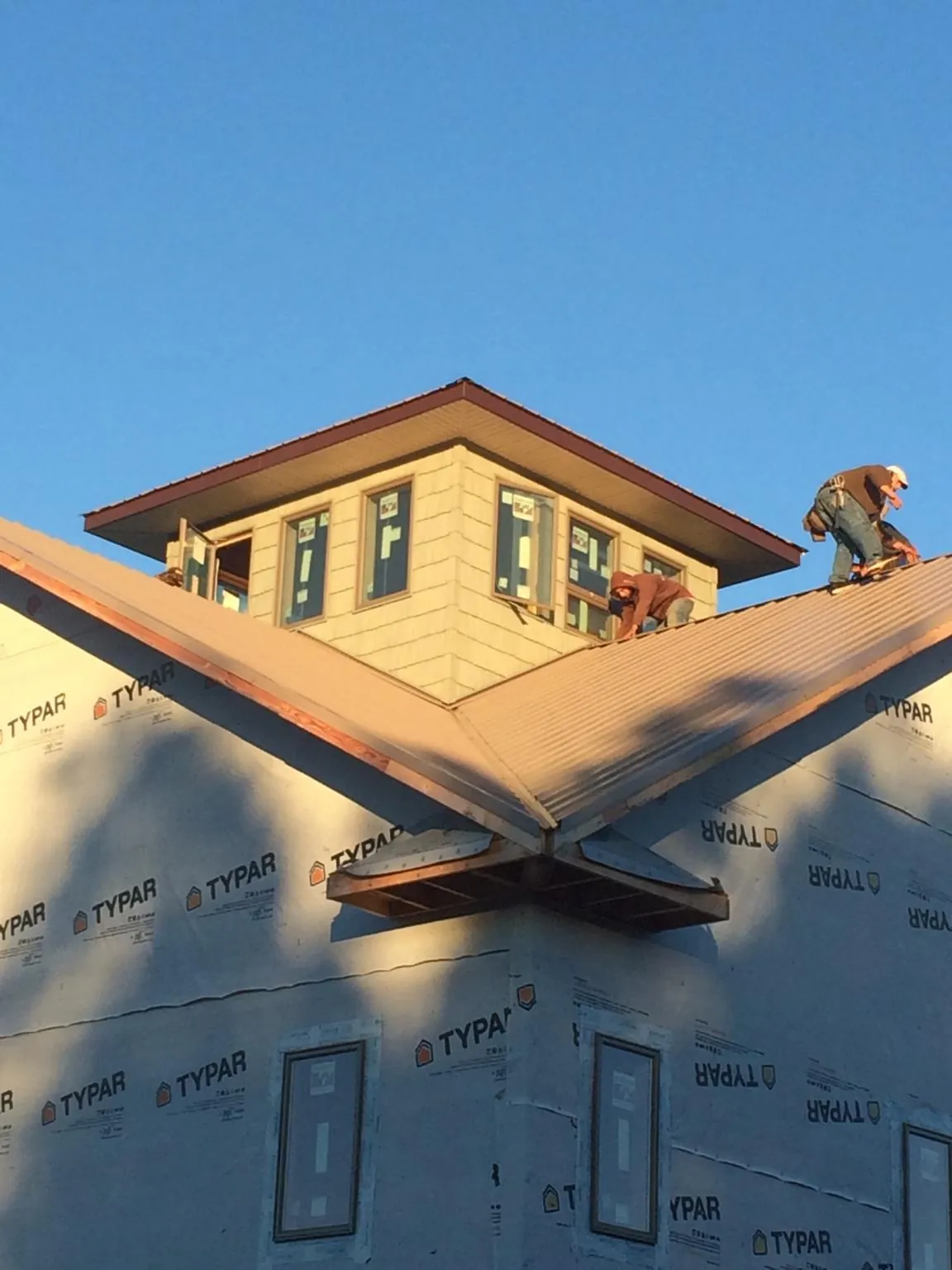 Roofers working around a rooftop cupola on a new metal roof at sunset — Roof Waterproofing in Shambaugh by Roofing Brothers